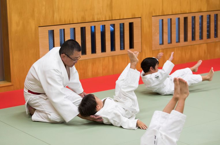 Judoleraar Tomoo Hamana beschermt tijdens een valtraining de nek van een jonge sporter.  Beeld AP