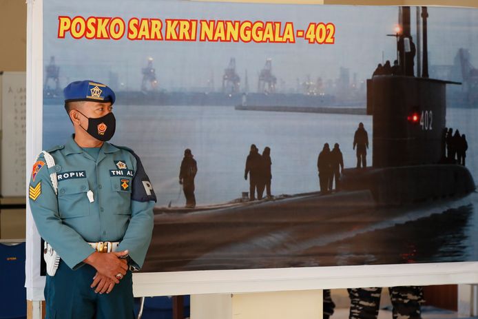Een militair staat voor een afbeelding van de vermiste duikboot KRI Nanggala-402.