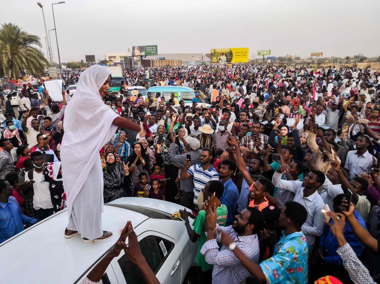 Een vrouw roept de menigte toe vanop een auto.  Beeld AFP