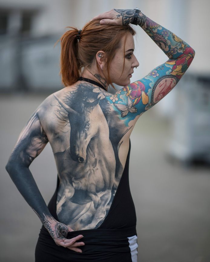 Een bezoeker van de internationale tattoo-conventie in het Duitse Frankfurt toont trots haar tattoo van een eenhoorn aan de fotograaf. Foto Boris Roessler