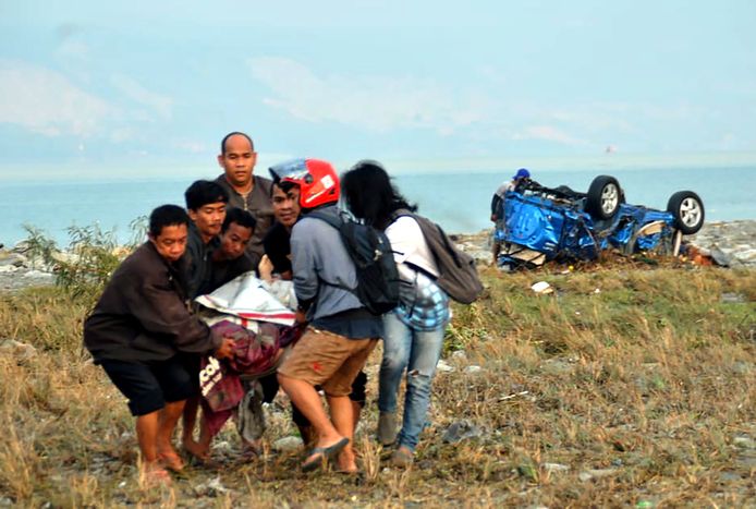 Mensen dragen een slachtoffer weg van de kust op Sulawesi.