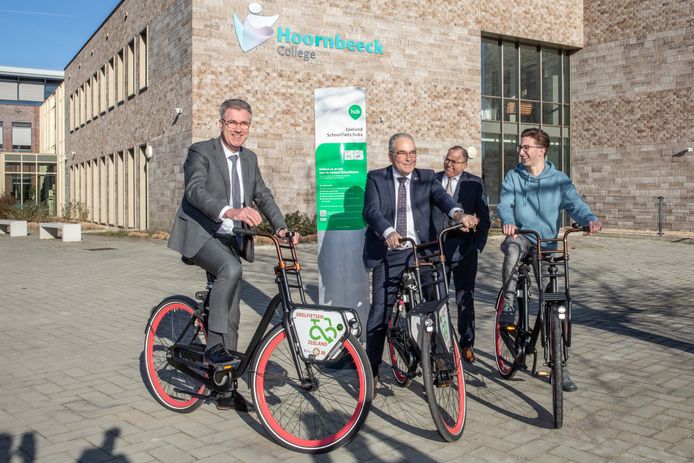 Vlnr: gedeputeerde Harry van der Maas, wethouder André van der Reest, schooldirecteur Evert Timmerman en student Leonard de Leeuw op een deelfiets voor het Hoornbeeck College in Goes.