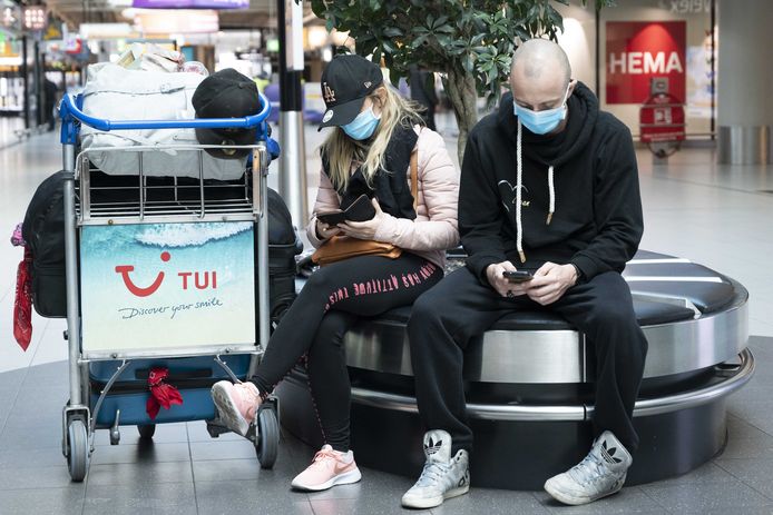 Reizigers met mondkapjes op luchthaven Schiphol.