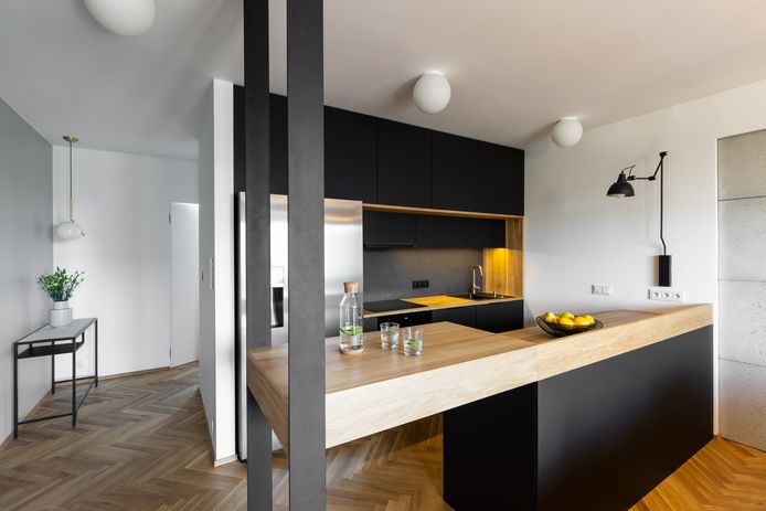 Modern huis: veel zwart en een houten vloer in visgraatpatroon.