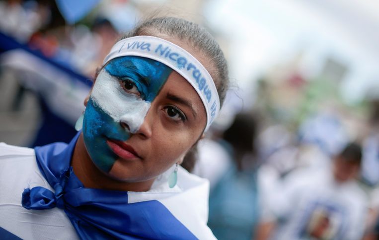Een studente heeft haar gezicht geschilderd in de kleuren van de Nicaraguaanse vlag. Beeld REUTERS