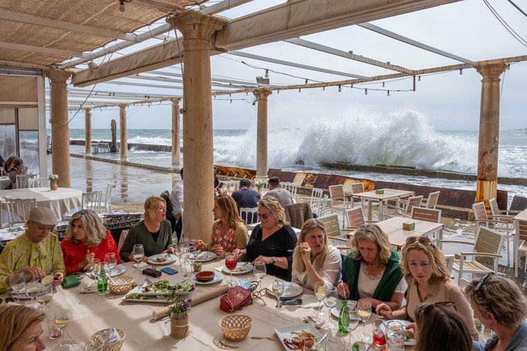 Een groep Nederlandse toeristen luncht bij restaurant El Balneario, dat sinds 1918 dicht op het water staat. Volgens lokale ondernemers zou een golfbreker voor de kust het water kunnen weghouden van het terras. Tegelijk is de nabijheid van het water ook een attractie voor veel gasten. Beeld Eline van Nes