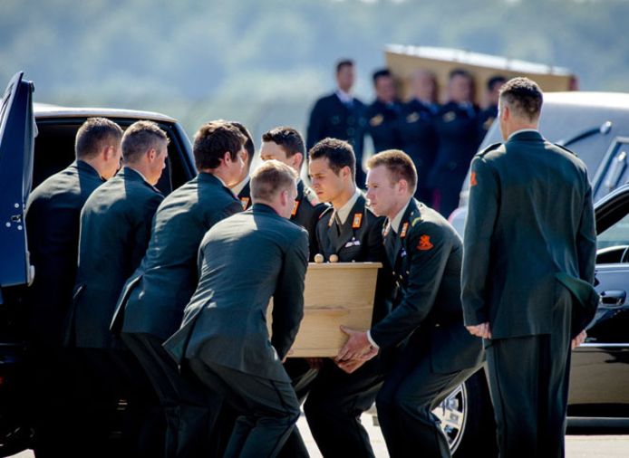 Militairen dragen op vliegbasis Eindhoven kisten met daarin de lichamen van slachtoffers van de vliegramp in Oekraïne.