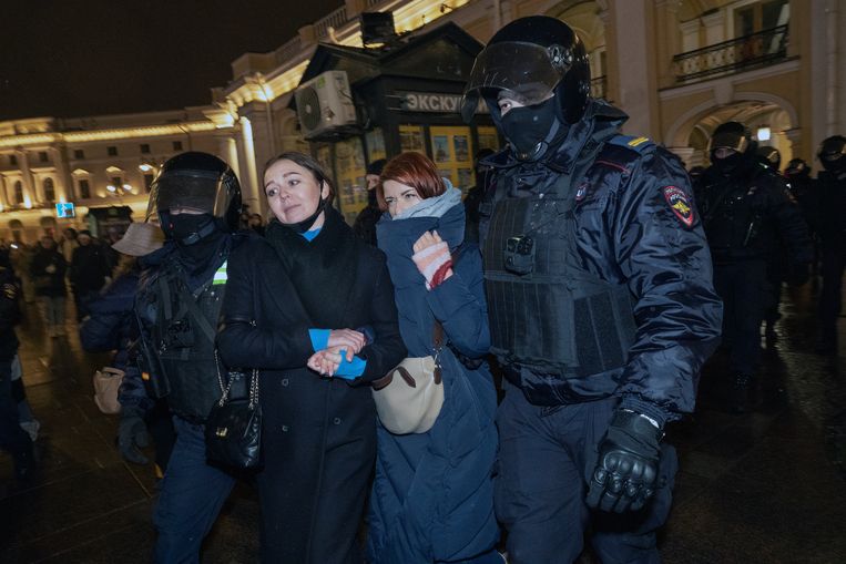  Russische politieagenten houden een demonstrant aan tijdens een betoging tegen de intocht van Russische troepen in Oekraïne in Sint-Petersburg. Beeld EPA