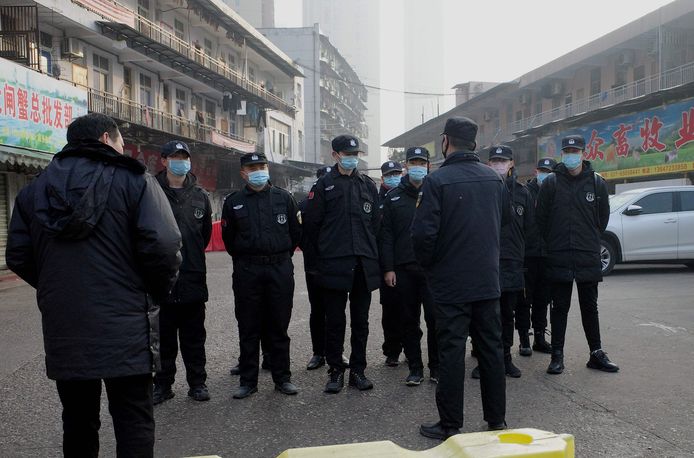 Politie met mondkapjes bij de gesloten vismarkt in Wuhan.