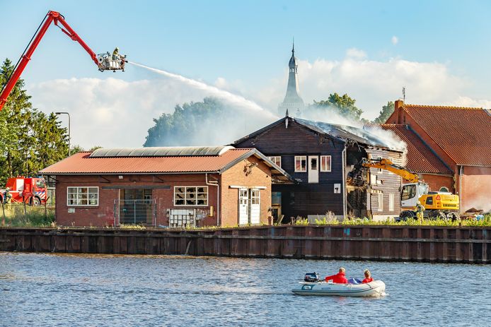 Uit voorzorg wordt het oude houten kantoorpand waar de brand woedde gesloopt. Boven het pand steekt de spits van de kerktoren van de Grote Kerk in Hasselt uit.