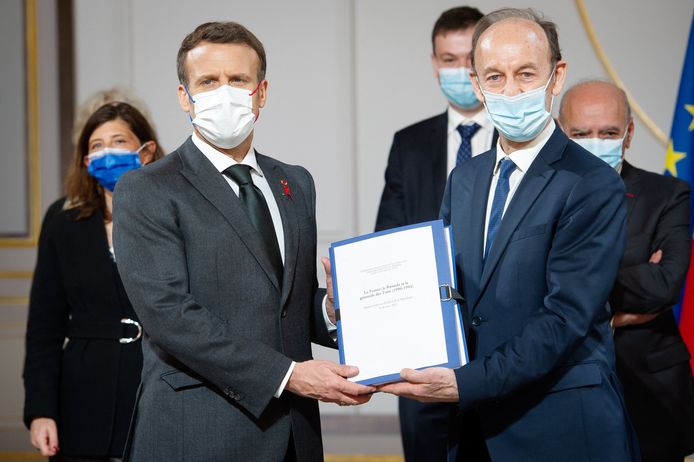 De Franse president Emmanuel Macron ontvangt het onderzoeksrapport van Vincent Duclert, voorzitter van de onderzoekscommissie.