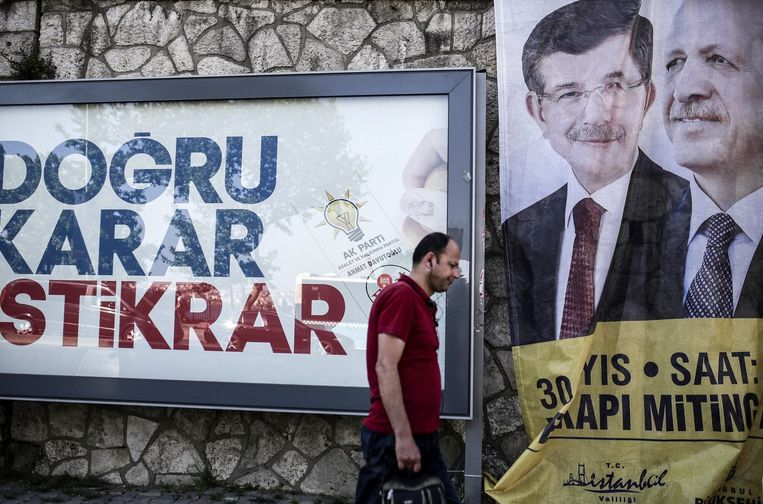 Een man loopt langs een verkiezingsposter met daarop Davutoglu en Erdogan Beeld afp