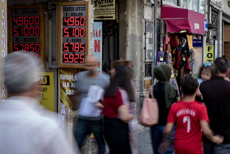 Inwoners van Istanbul lopen langs een geldwisselkantoor. Op valutaborden de lage waarde van de lira ten opzichte van de dollar. Beeld Getty Images