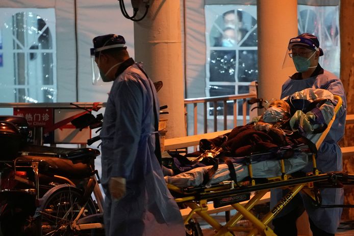 Medisch personeel met een coronapatiënt aan een koortkliniek van een ziekenhuis in Shanghai.