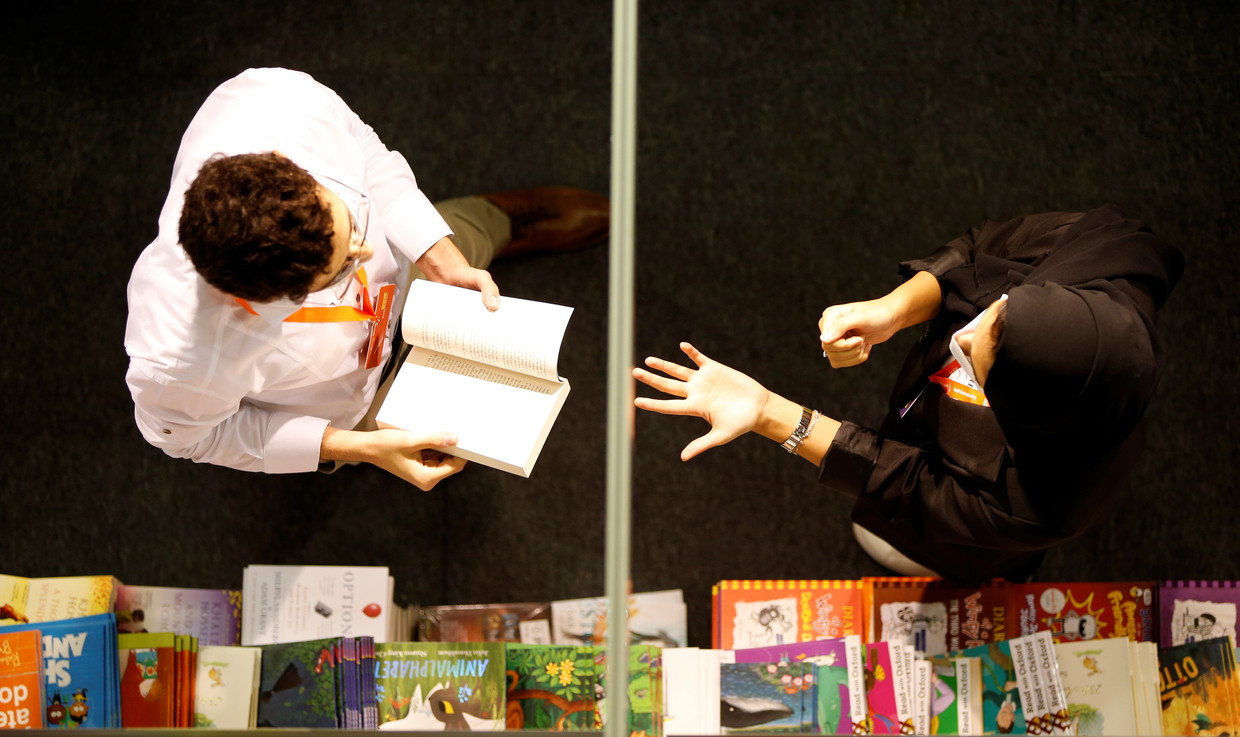 Een man en een vrouw praten met elkaar op de Internationale Boekenbeurs in Sharja, Verenigde Arabische Emiraten.  Beeld EPA