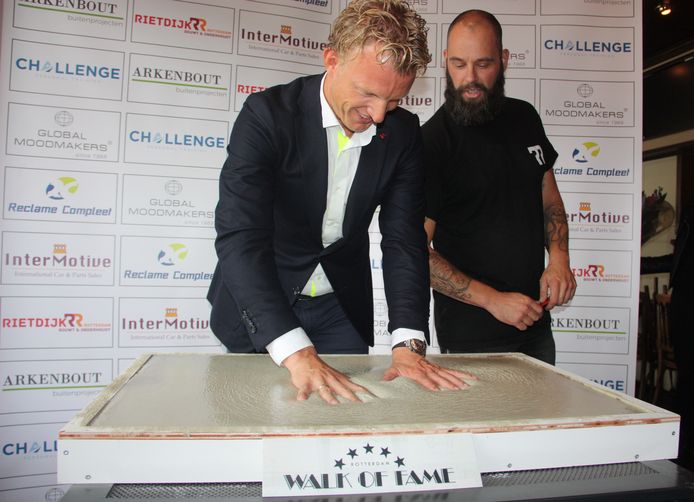 Dirk Kuyt drukt onder het toeziend oog van tegelmaker Patrick de Jong van Rietdijk Rotterdam zijn handen in het beton.