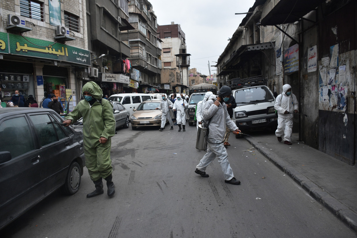 Syrische gemeentewerknemers steriliseren de straten van Damascus om verdere verspreiding van Covid-19 te voorkomen. Beeld Hollandse Hoogte / EPA