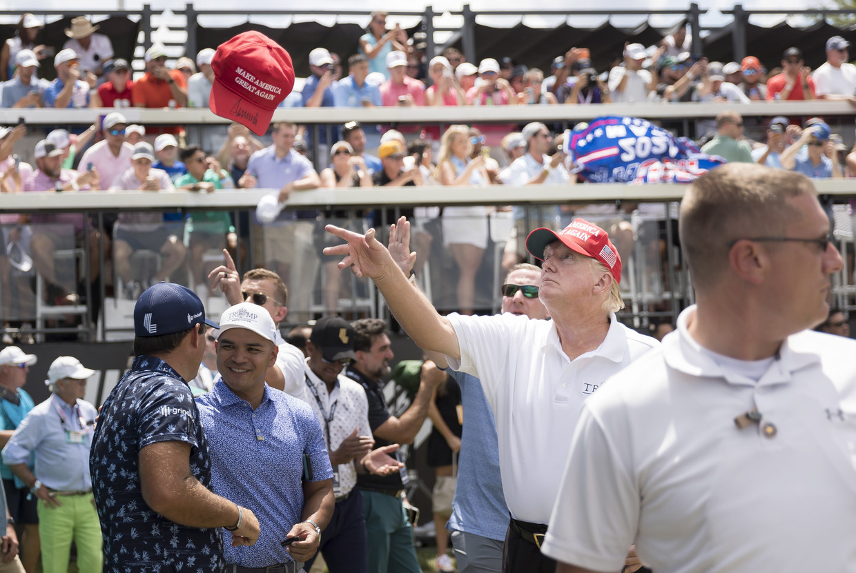 Voormalig VS-president Donald Trump gooit een pet naar een fan tijdens een golftoernooi in New Jersey. Beeld ANP / EPA