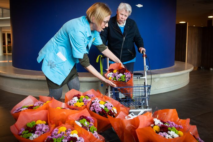 Wijkverpleegkundige Annemiek Vissers deelt het eerste boeket uit aan Riet Frijters.