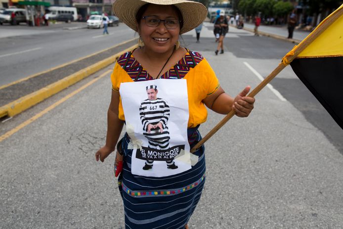 Een vrouw met een karikatuur van de Guatemalteekse president Jimmy Morales in gevangeniskleren.