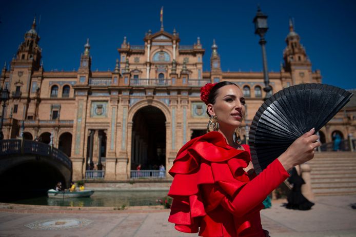 Een vrouw in een traditionele Andalusische jurk probeert verkoeling te vinden in Sevilla.