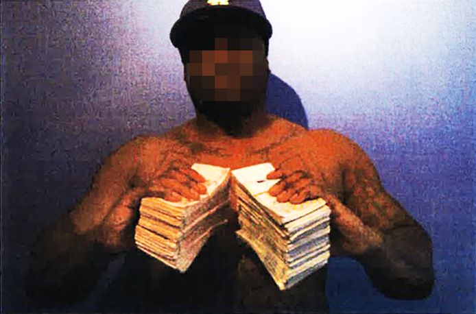 Delano R. poserend met grote stapels geld. Deze foto is opgenomen in het strafdossier van R.