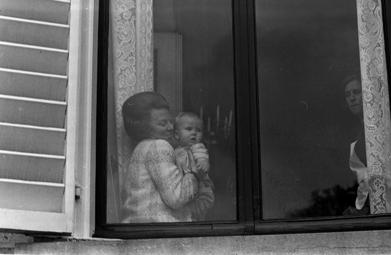 Koninginnedag 1968: Prins Willem-Alexander op de schoot van zijn moeder achter een van de ramen van Paleis Soestdijk. De kleine prins kijkt een beetje bedremmeld naar de drukte in de paleistuin. Beeld ANP /  ANP