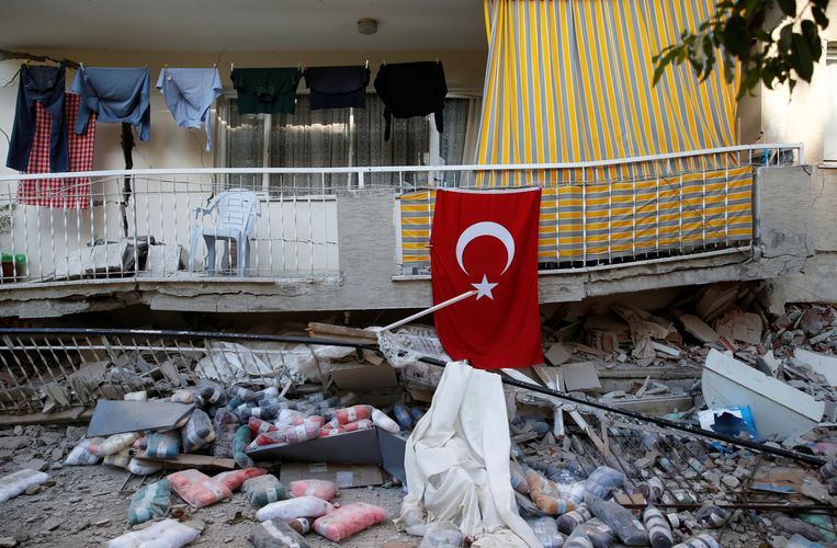 Een Turkse vlag bij een verwoest huis in Izmir. Beeld REUTERS