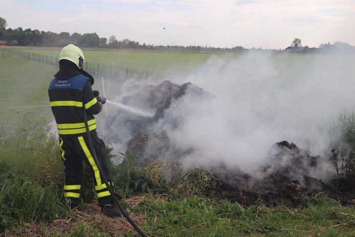 Brandweer blust brandende berg gras in Wijk en Aalburg
