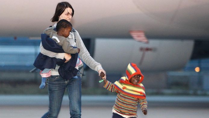 Een adoptiemoeder haalt twee adoptiekinderen op bij Eindhoven Airport. 106 kinderen werden in 2010 in Nederland opgevangen na de aardbeving in Haïti.