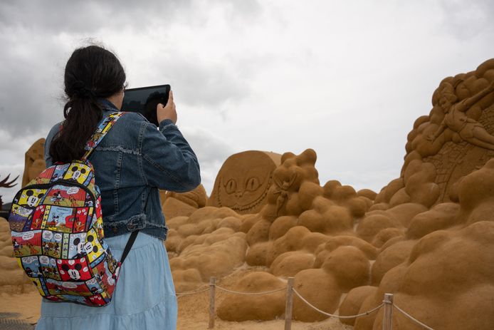 Een meisje fotografeert zandsculpturen aan de Belgische kust.