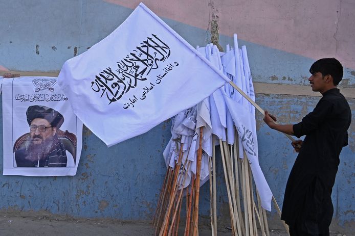 Een straathandelaar zet nieuwe handel klaar, onder meer talibanvlaggen en posters van Abdul Ghani Baradar, de nieuwe sterke man.