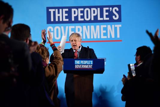 Boris Johnson spreekt partijgenoten toe onder het nieuwe logo: 'De regering van het volk'. 
