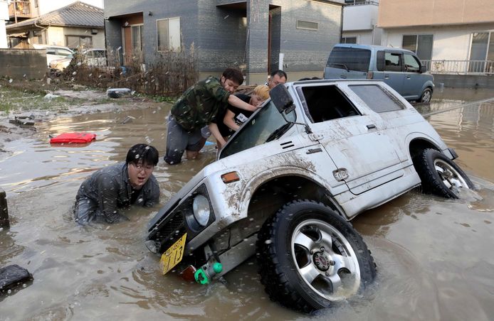 Mensen proberen een ondergelopen auto te redden in Kurashiki, in de prefectuur Okayama.