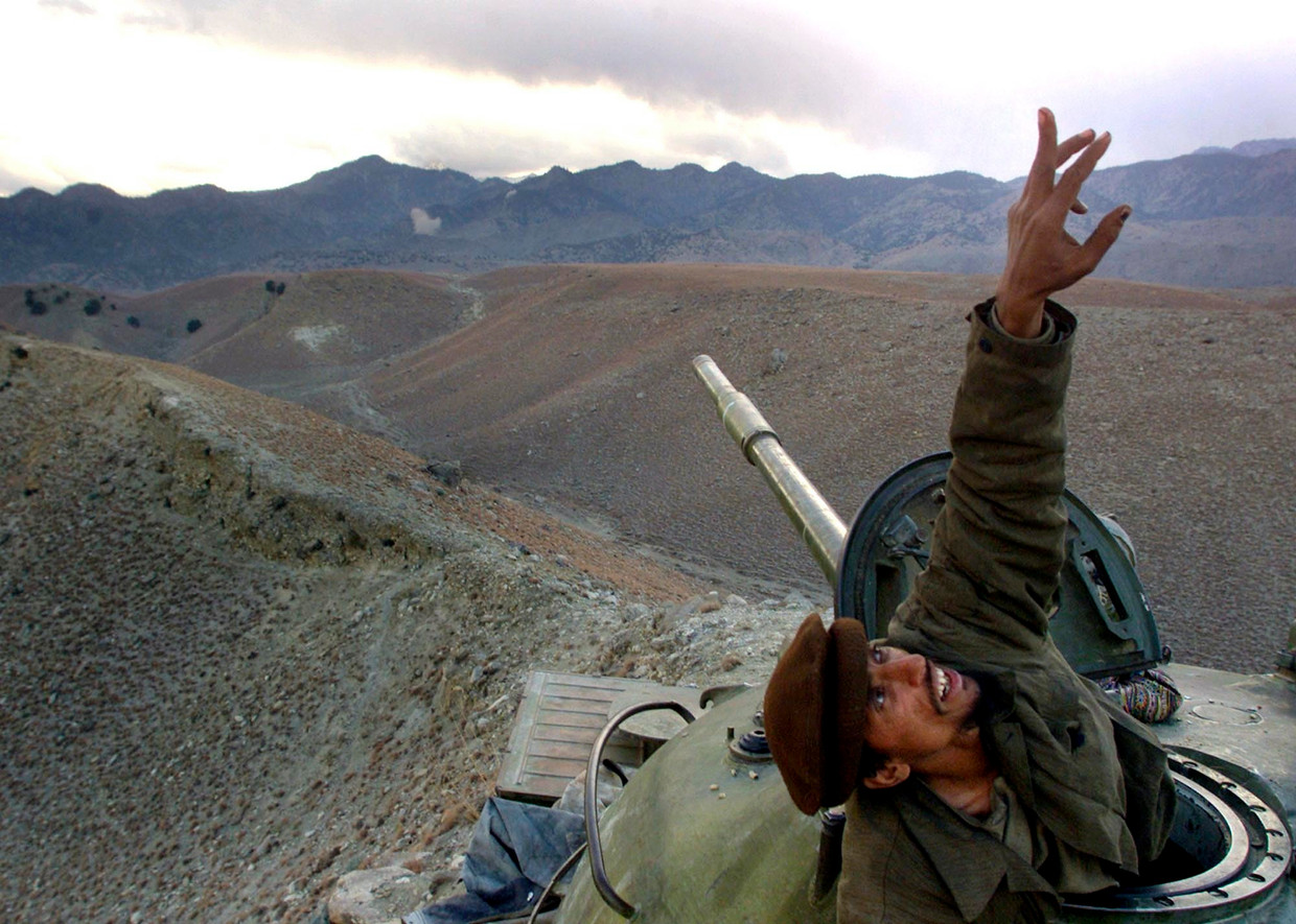 Een anti-Talibanstrijder wijst vanuit zijn tank op een Amerikaanse bommenwerper, die de Taliban vanuit de lucht komt bestoken in het gebied Tora Bora, december 2001. De steun aan anti-Talibanmilities zou in de jaren daarop enorme gevolgen hebben.  Beeld AP
