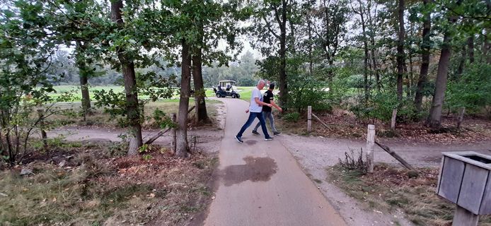 Wandelaars op het openbare pad kruisen op golfbaan The Duke de verharde verbinding tussen de holes 11 en 12.