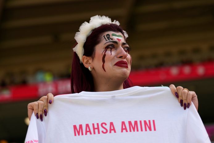 Een Iraanse supporter huilt als zij een shirt met de naam 'Mahsa Amini' vasthoudt aan het begin van de WK-wedstrijd tussen Wales en Iran.