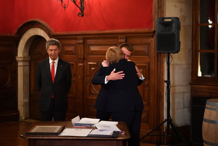 De Franse president Emmanuel Macron omhelst vertrekkend Duits bondskanselier Angela Merkel. Links Merkels echtgenoot Joachim Sauer. Beeld EPA