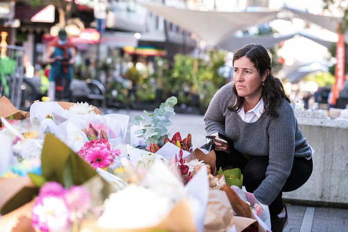 Een vrouw legt bloemen neer bij het winkelcentrum waar het drama plaatsvond.