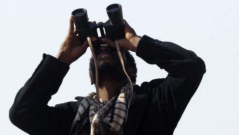 Een Libische opstandeling kijkt naar een overvliegend coalitievliegtuig. Beeld reuters