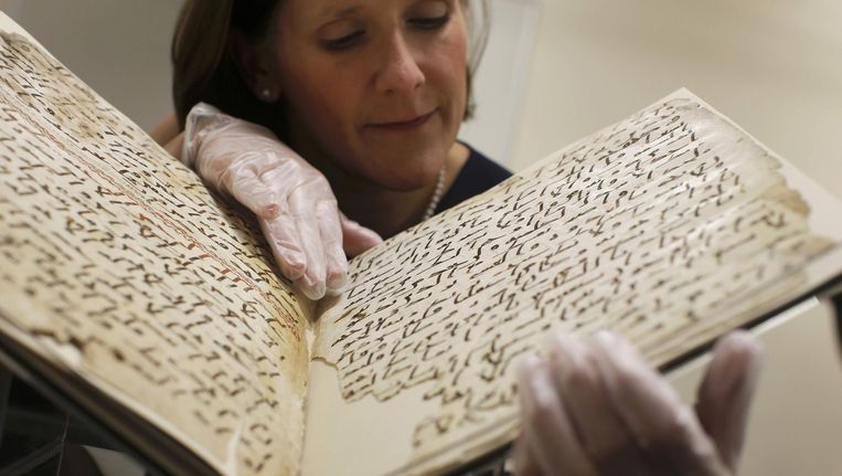 Conservator Marie Sviergula houdt het pas ontdekte stuk Koran vast in de bibliotheek van de Universiteit van Birmingham. Beeld reuters