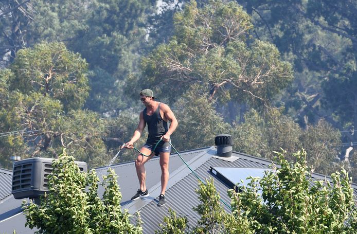 Een man is het dak van zijn huis aan het afkoelen in Melbourne. Intussen is het te laat om het gebied nog te ontvluchten, want al heel wat bossen in het westen van Victoria staan intussen in brand.