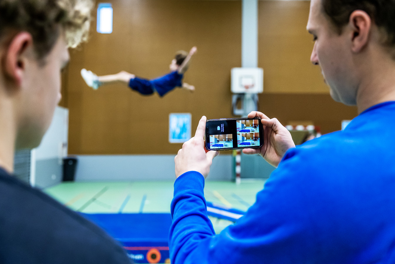 Samen met gymdocent Olaf Remmerswaal bekijkt een leerling zijn sprong terug. Op X11, een middelbare school voor media en vormgeving, is de smartphone bijna niet weg te denken uit de lessen.