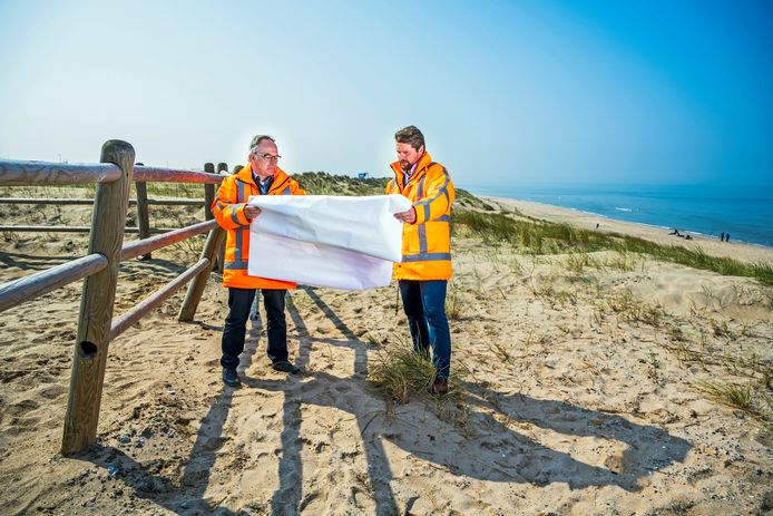 Rien van Zetten (l) en  Teun Lamers van Rijkswaterstaat bestuderen nog even de kaart waar de windmolens komen. Achter hen is een van de plekken waar een witte reus komt te staan.