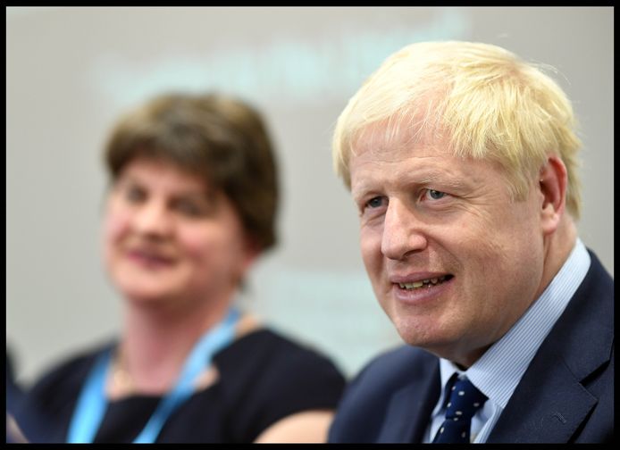 Boris Johnson met achter hem onscherp in beeld DUP-leider Arlene Foster.