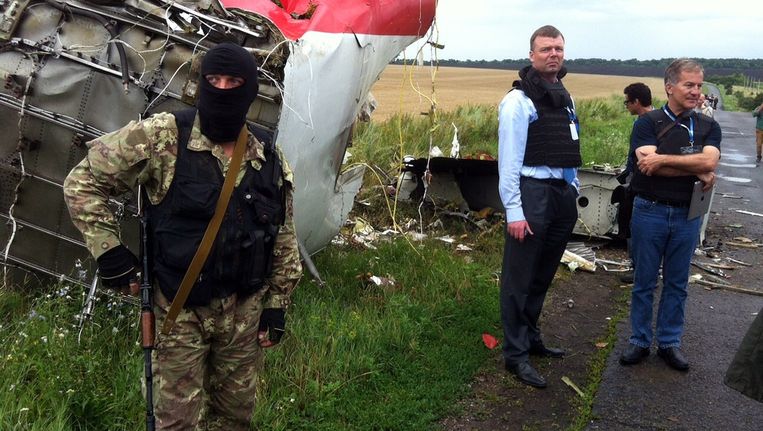 Een separatist bij de rampplek. In het midden Alexander Hug, plaatsvervangend hoofd van de OVSE-missie in Oekraïne. Beeld afp