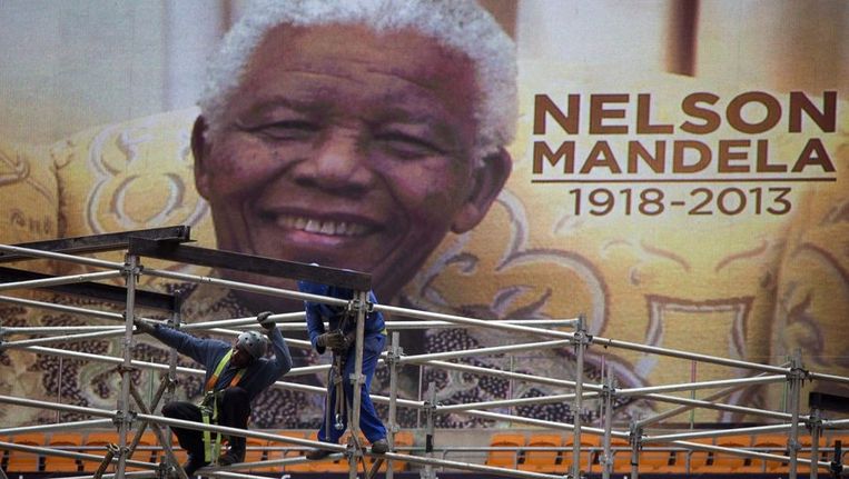 Een van de afbeeldingen van Nelson Mandela die aan de buitenzijde van het FNB-stadion in Johannesburg, ook wel bekend als Soccer City, worden bevestigd. Beeld reuters