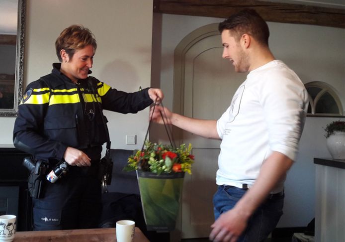 Jim Muller uit Elshout krijgt een bloemetje van wijkagent Belinda van der Genugten als dank voor zijn heldendaad.