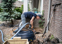 Iwan Fransen is bezig met het installeren van een watertank met pomp die het regenwater opvangt.