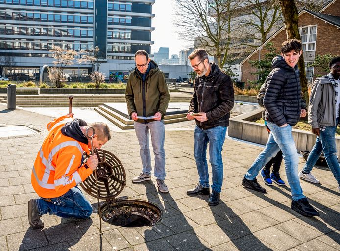 Toezichthouder Vincent Mulder (links) checkt het waterpeil van het Benthemplein. Rotterdam loopt met waterpleinen voorop, zeggen Jason Zondag (met baard) en Paul Boshart (midden) van de gemeente Rotterdam.